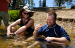 © Gary Radler Photography/Stocksy - Two Men Sharing a Joke while Wading in River