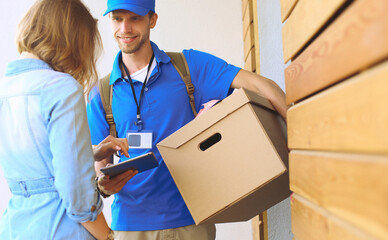 Smiling delivery man in blue uniform delivering parcel box to recipient - courier service concept