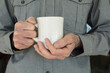 © David Smart/Stocksy - Man holding a white coffee mug with both hands