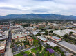 an aerial view of the city of Pasadena California with blue sky and interesting cloud covers with buildings and purple trees in the cityscape and mountain ranges USA