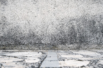 Wall Mural - Cobblestone floor and concrete wall in the city. Stone floor and wall background. Close-up view of the street floor.