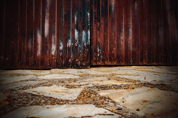 Wall Mural - Cobblestone floor and aged wooden door in the city. Stone floor and wall background. Close-up view of the street floor.