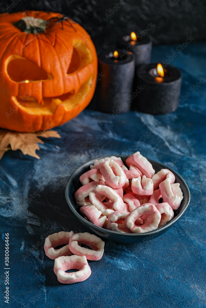 Bowl with tasty treats for Halloween on dark background