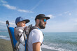 © ACALU Studio/Stocksy - Father carrying his son in a backpack near the sea