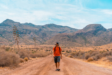 Wall Mural - A young man walking along a desert path in the natural park of Cabo de Gata, Nijar, Andalusia. Spain, Mediterranean Sea