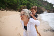 © Rob and Julia Campbell/Stocksy - Fun loving grandma with kids on tropical beach
