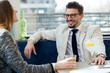 © Guille Faingold/Stocksy - Young business couple drinking something at a coffee shop.