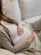 © Laura Stolfi/Stocksy - Close up of pregnant woman with hands on her 6 months belly