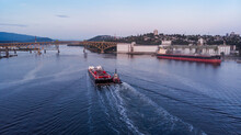 Aerial Drone Shot Of A Single Tug Boat And The Port Facilities In The Harbor Of Vancouver, BC, Canada.