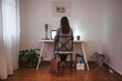 © BONNINSTUDIO/Stocksy - Back view of woman working on white desktop on home office.