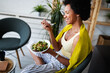 © NDABCREATIVITY - Beautiful afro american woman eating vegetable salad at home.