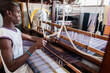 © Caine Delacy/Stocksy - Young African Man uses a loom to make material in workshop