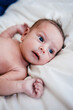 © Cara Dolan/Stocksy - Newborn baby lies on bed, looking around