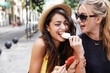 © Guille Faingold/Stocksy - Happy young women sharing ice cream on street