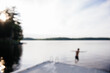 © Cara Dolan/Stocksy - Child swimming in a lake from a dock, defocused