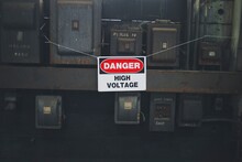 A Danger High Voltage Hangs On Some Old Dirty Electrical Boxes.