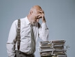 © stokkete - Pensive businessman leaning on a pile of paperwork