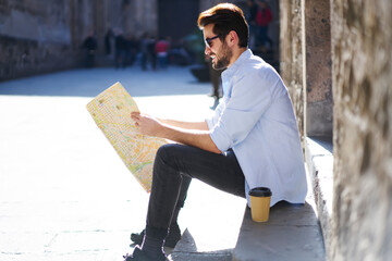 Wall Mural - Cheerful man looking for landmarks on map