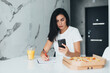 © F8  \ Suport Ukraine - Portrait of young woman eating pizza and use phone while working from home