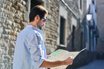 Wall Mural - Pensive young man checking direction on map