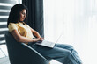 © F8  \ Suport Ukraine - Young smiling woman is sitting on modern chair at home working on laptop in relaxing atmosphere