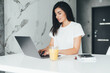© F8  \ Suport Ukraine - Attractive young woman using laptop and sitting in the kitchen