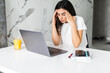 © F8  \ Suport Ukraine - Confused displeased young woman sitting indoors at kitchen using laptop