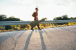 © Inuk Studio/Stocksy - Man walking with his guitar and bag on the roadside at sunset