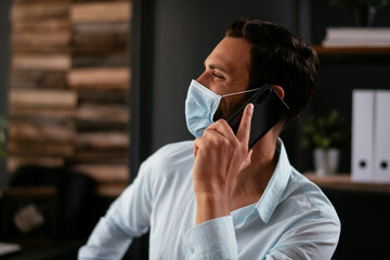 Businessman with medical mask. Handsome businessman talking to the phone.