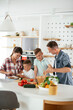 © JustLife - Mother and father making breakfast with sons. Young family preparing delicious food in kitchen