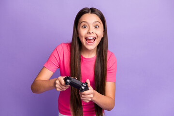 Poster - Photo portrait of young schoolgirl playing video games holding gamepad with both hands screaming laughing wearing pink casual t-shirt isolated on purple color background