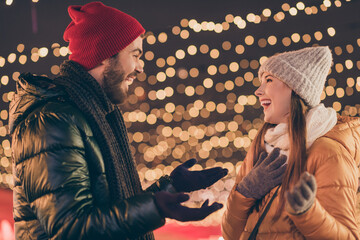 Sticker - Photo of two friends guy speaking with girl on x-mas party under evening tradition illumination wear scarf hat