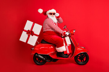 Poster - Full length profile photo of grandfather grey beard ride retro moped deliver box wear santa claus x-mas costume suspenders sunglass striped shirt cap boots isolated red color background