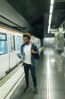 © BONNINSTUDIO/Stocksy - Afro black man reading a book while waiting the subway train.