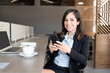 © AntonioDiaz - Smiling businesswoman using mobile phone at desk