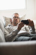 © Tetra Images - Man lying on sofa using phone