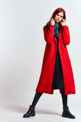 emotional woman in a red coat and with a hat in full growth on a light background black boots pose model