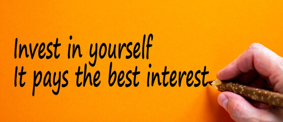 Wall Mural - Hand writing 'invest in yourself it pays the best interest', isolated on orange background. Business concept, copy space.