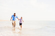 © Tetra Images - Father and son (10-11) running on beach