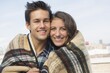 © Jamie Grill/Tetra Images - Portrait of young couple wrapped in blanket