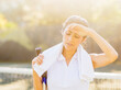 © Tetra Images - Portrait of young woman with towel and tennis racket wiping forehead with back of hand