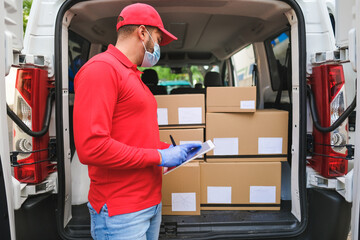 Delivery man checking with digital tablet the package while wearing protective face mask for coronavirus - Work with new safety mesaures