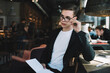 © BullRun - Young thoughtful businessman with organizer in crowded cafe