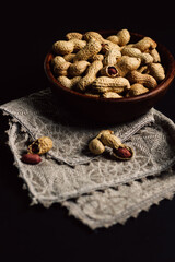 peanuts in a wooden plate on a black background