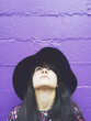 © Sky-Blue Images/Stocksy - Woman against a purple wall looking up