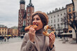 Woman eating bagel obwarzanek traditional polish cuisine snack on Market square in Krakow. Travel Europe in autumn