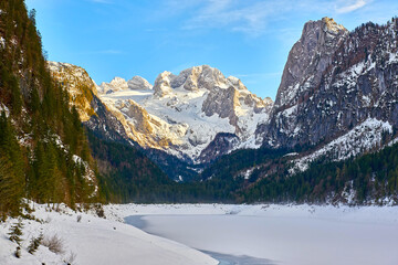 Beautiful Gosausee lake landscape with Dachstein mountains, forest, clouds and snow in Austrian Alps