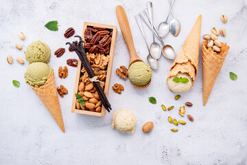 Fototapete - Pistachio and vanilla ice cream in cones  with mixed nut setup on white stone background . Summer and Sweet menu concept.