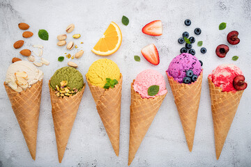 Fototapete - Various of ice cream flavor in cones blueberry ,pistachio ,almond ,orange and cherry setup on white stone background . Summer and Sweet menu concept.