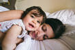 © Inuk Studio/Stocksy - Cute moment of a mother and her daughter smiling and lying on a bed